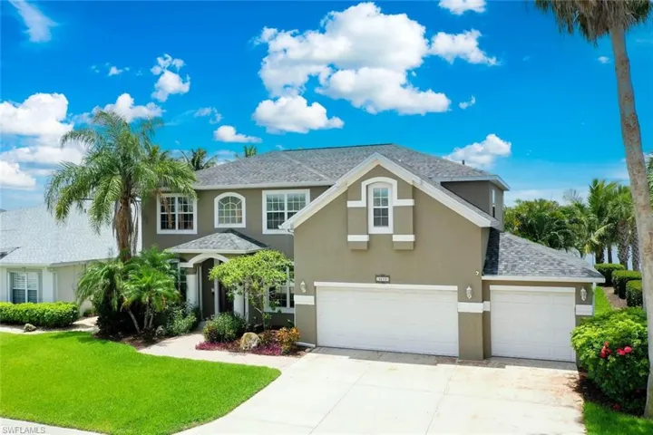 Traditional-style house with stucco siding, a front yard, a shingled roof, and driveway