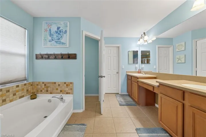 Primary bathroom featuring double vanity, tile patterned floors, and a garden tub