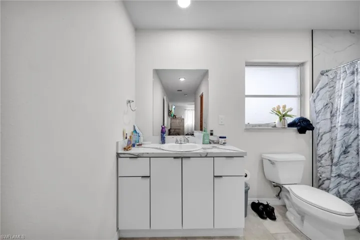Bathroom featuring vanity, toilet, baseboards, curtained shower, and recessed lighting