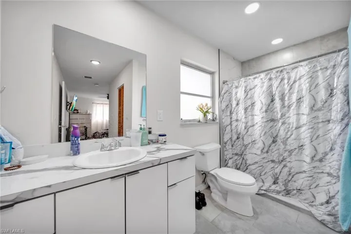 Full bathroom with vanity, toilet, curtained shower, and recessed lighting
