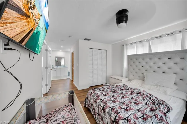 Bedroom with wood finished floors, a closet, and baseboards