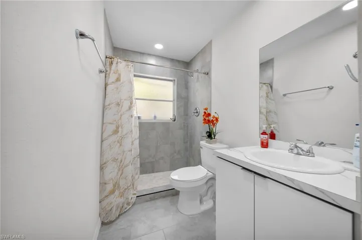 Bathroom with vanity, toilet, and tiled shower