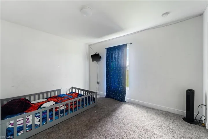 Carpeted bedroom featuring a nursery area and baseboards