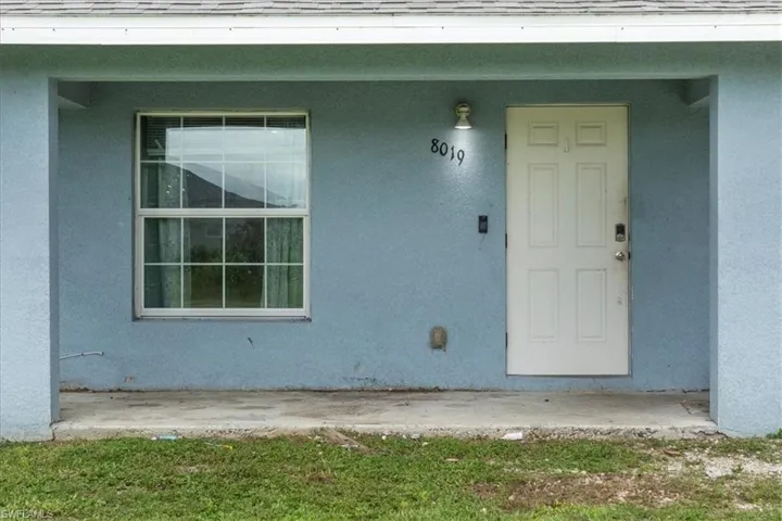 View of exterior entry with roof with shingles and stucco siding