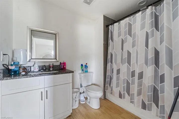 Full bathroom with vanity, light wood-type flooring, and curtained shower