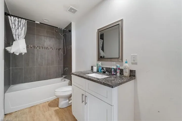 Full bathroom with shower / tub combo, vanity, and light wood-style floors