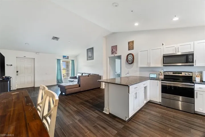 Kitchen with stainless steel appliances, white cabinets, a peninsula, open floor plan, and dark stone countertops