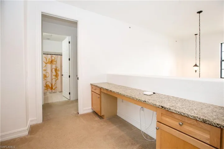 Unfurnished office featuring light colored carpet and built in desk