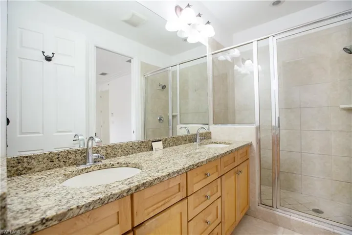 Bathroom with tile flooring, a shower with glass shower door, oversized vanity, and double sink