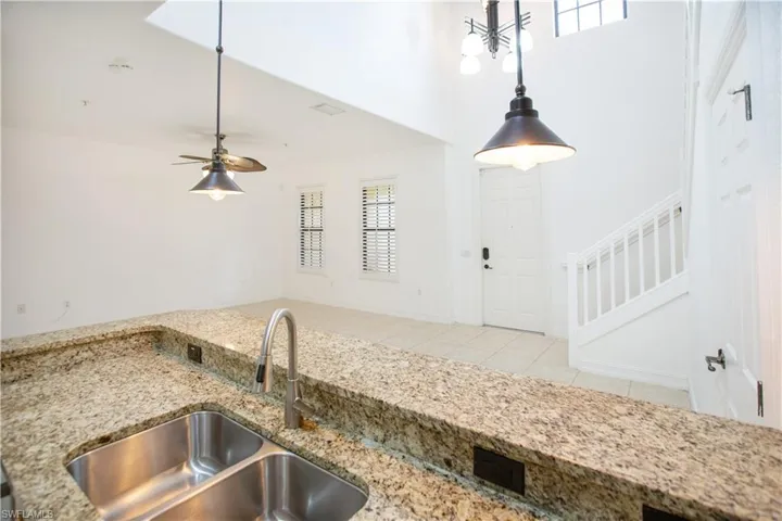 Kitchen with decorative light fixtures, sink, and a healthy amount of sunlight