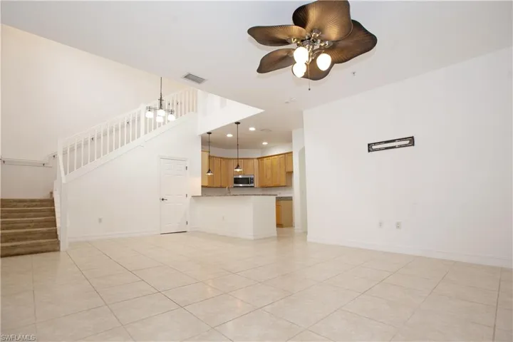Unfurnished living room featuring ceiling fan and light tile floors