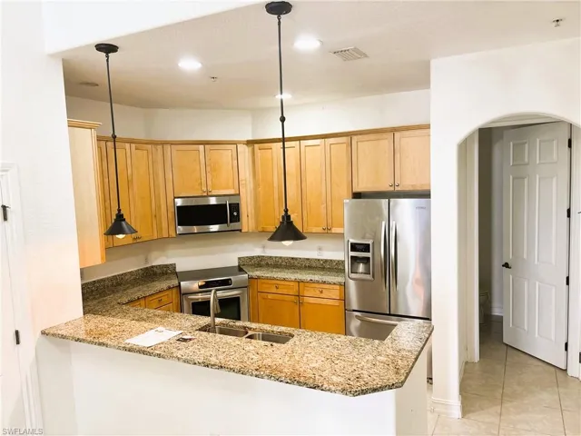 Kitchen featuring visible vents, a peninsula, light stone countertops, stainless steel appliances, and arched walkways