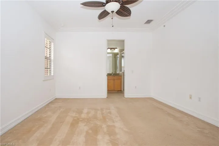 Master bedroom with light carpet, crown molding, and ceiling fan