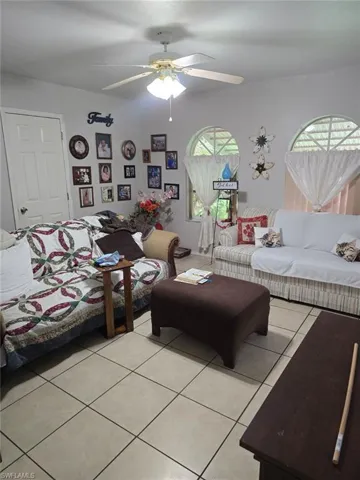 Living room featuring plenty of natural light, light tile patterned flooring, and a ceiling fan