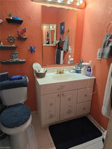 Bathroom featuring a textured wall, light tile patterned flooring, and vanity