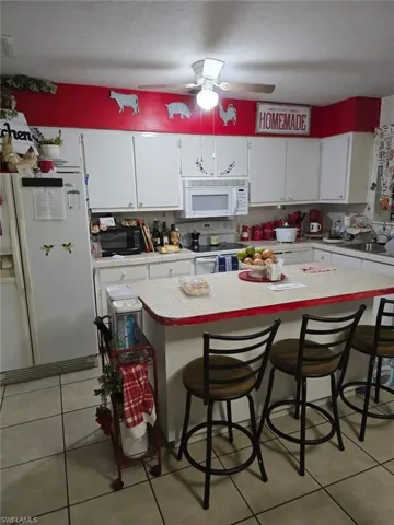 Kitchen with white cabinetry, white appliances, tile countertops, and light tile patterned floors
