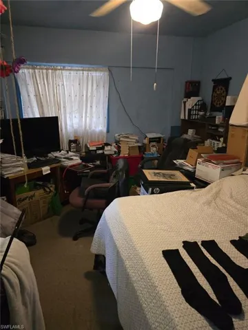 Carpeted bedroom featuring an office area and a ceiling fan