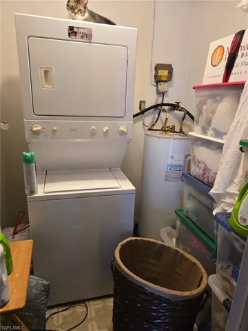 Washroom featuring stacked washing machine and dryer and electric water heater