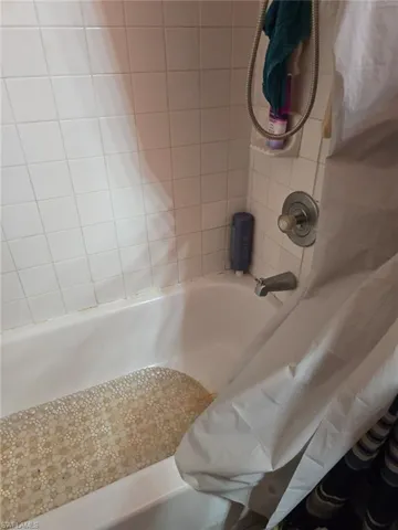 Bathroom view of shower / bathtub combination with curtain