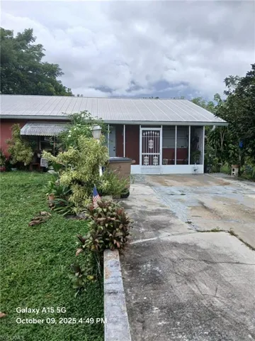featuring a metal roof, driveway, and a sunroom