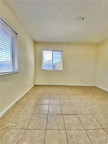 Empty room featuring a textured ceiling and light tile patterned floors