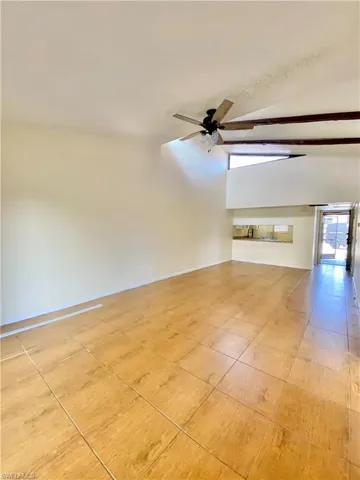 Unfurnished living room featuring vaulted ceiling, light tile patterned floors, and a ceiling fan