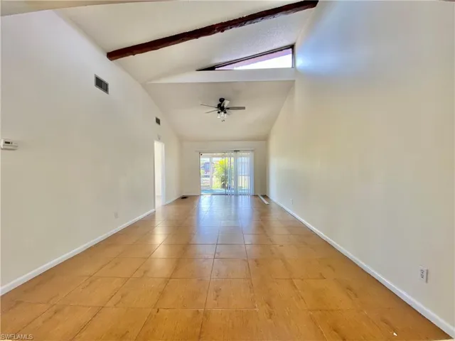 Spare room with beamed ceiling, high vaulted ceiling, light tile patterned flooring, and ceiling fan