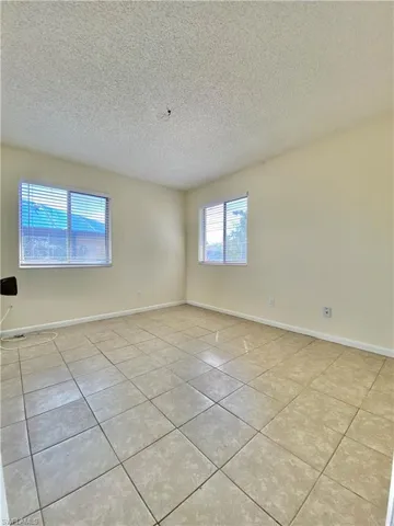 Unfurnished room featuring a textured ceiling and light tile patterned flooring