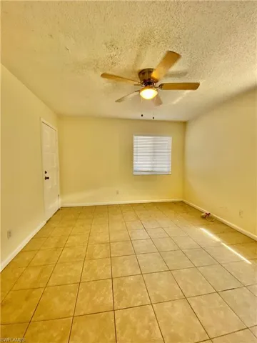 Spare room with light tile patterned floors, ceiling fan, and a textured ceiling