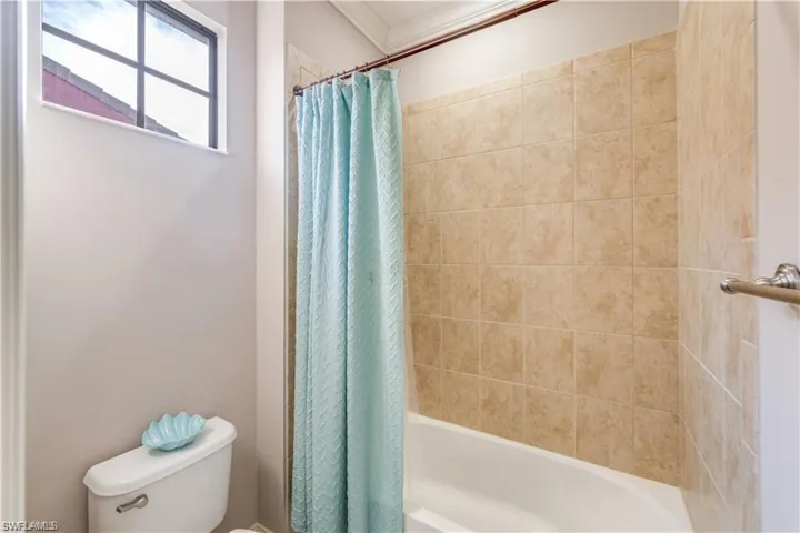 Bathroom featuring shower / tub combo and ornamental molding