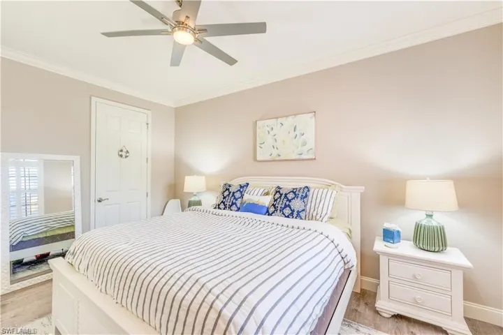 Bedroom with ornamental molding, light wood-type flooring, and a ceiling fan