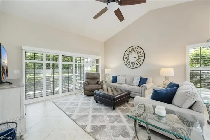 Living area with ceiling fan, light tile patterned floors, and high vaulted ceiling
