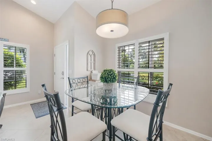 Dining room with light tile patterned flooring and a towering ceiling