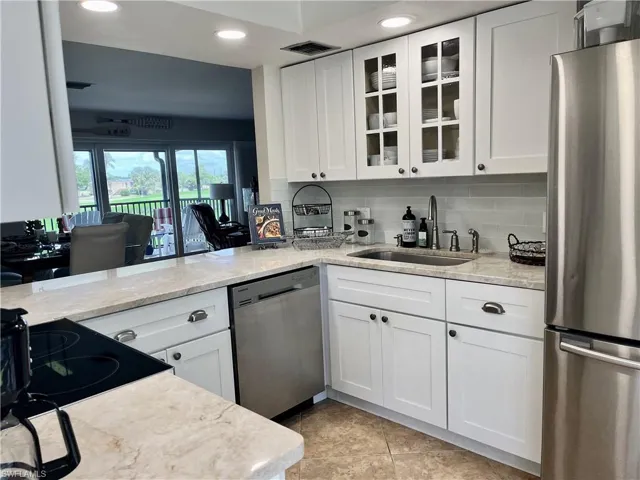 Updated Kitchen with stainless steel appliances, recessed lighting, glass insert cabinets, white cabinets, and tile flooring