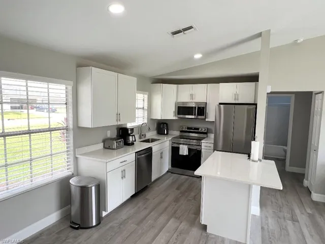 Kitchen featuring light wood-type flooring, sink, stainless steel appliances, and white cabinets
