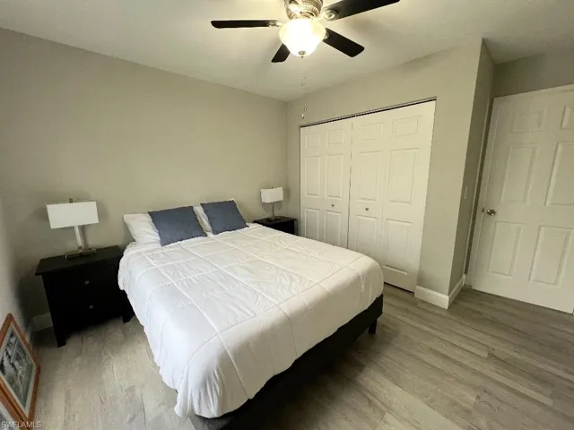 Bedroom with ceiling fan, wood-type flooring, and a closet