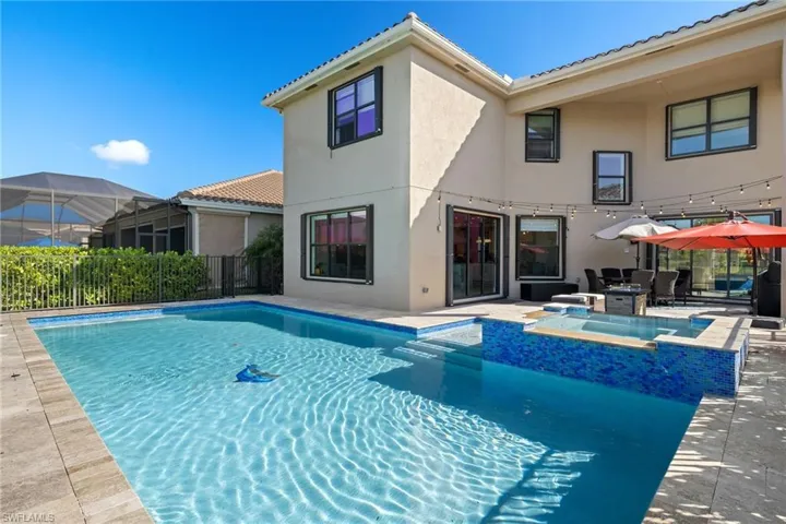 View of pool featuring a patio, glass enclosure, and an in ground hot tub