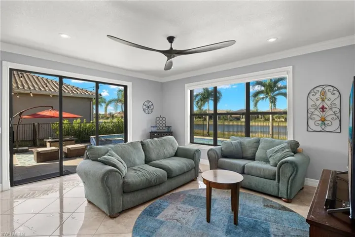Great Room with stacked white tone wall with ceiling fan, a water view, and ornamental molding