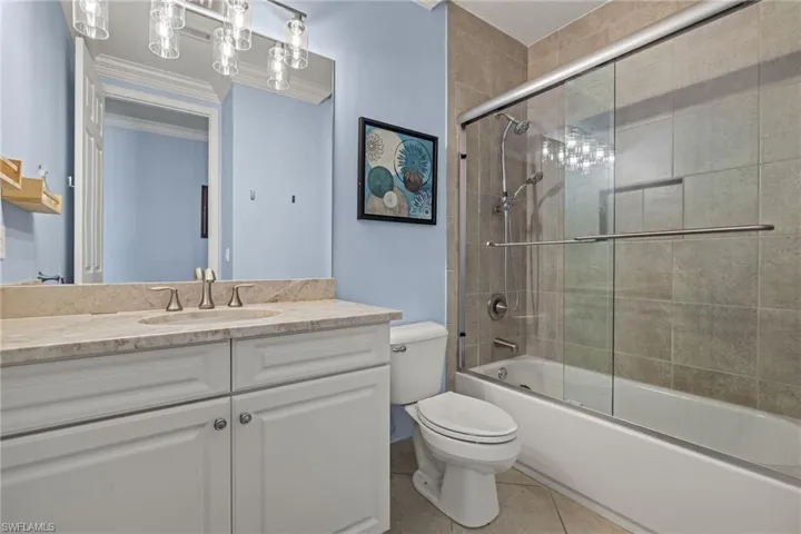 Full bathroom with combined bath / shower with glass door, tile patterned floors, vanity, and toilet