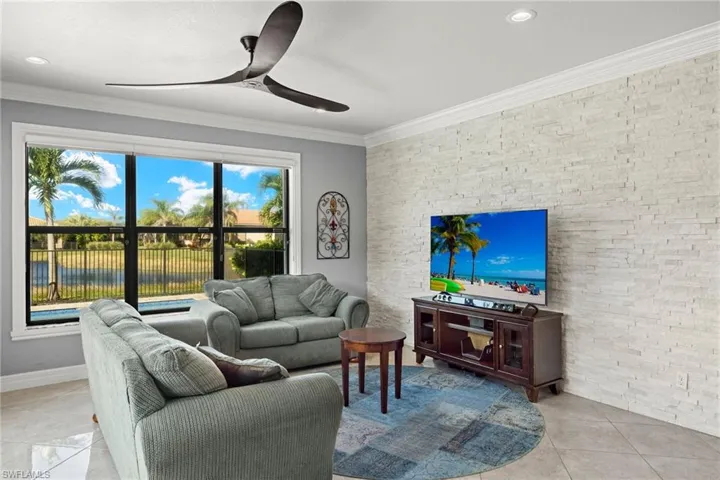 Great Room stacked white wall feature, tons of light with ornamental molding and ceiling fan and 20 x 20 porcelain tile