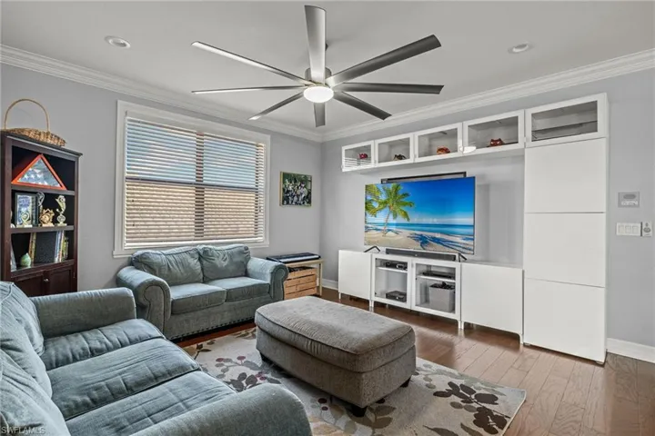 Loft featuring ceiling fan, hardwood / wood-style flooring, and ornamental molding