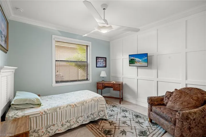 Tiled bedroom featuring ornamental molding and ceiling fan