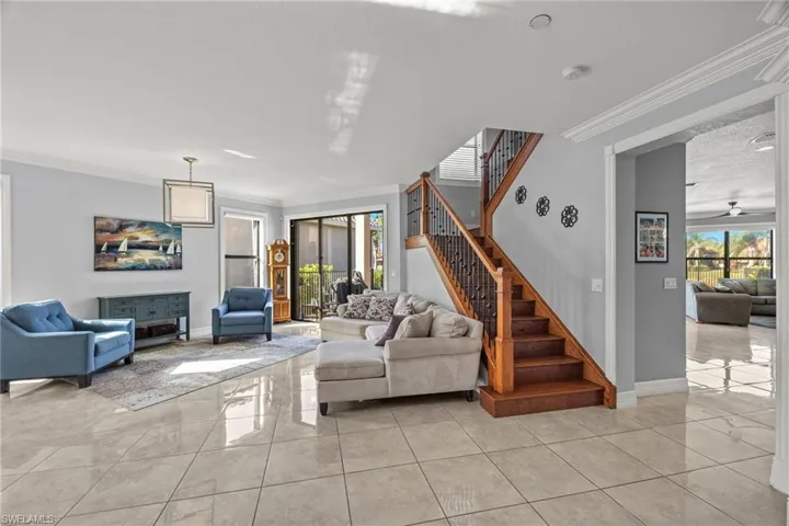 Living room with a textured ceiling, light tile patterned floors, crown molding, and ceiling fan