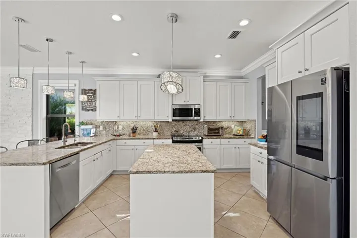 Kitchen with pendant lighting, appliances with stainless steel finishes, sink, and a center island