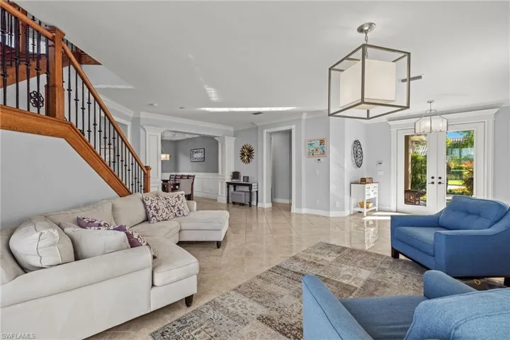 Living room with decorative columns, a chandelier, and ornamental molding