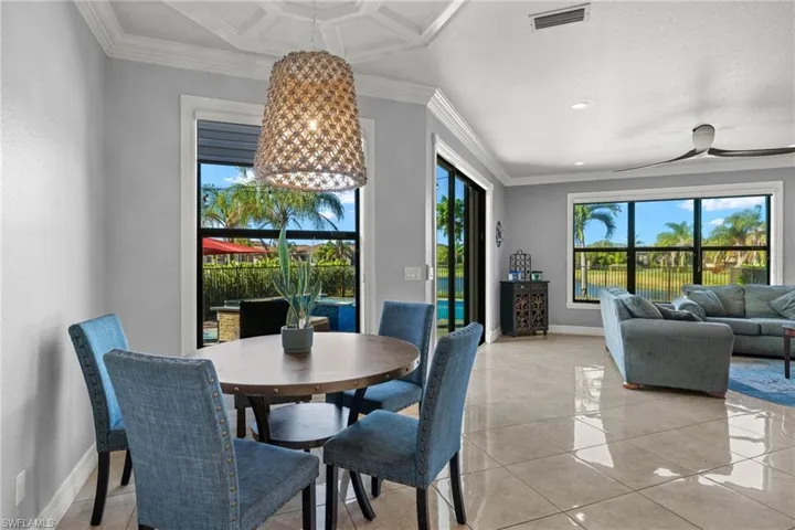 Dining area with light tile patterned floors, crown molding, and coffered ceiling