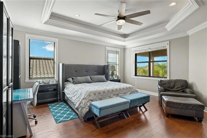 Enormous Bedroom Suite with ornamental molding, wood-type flooring, multiple windows, and ceiling fan