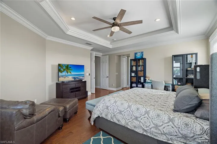 Enormous Bedroom Suite featuring ornamental molding, a raised ceiling, ceiling fan, and dark hardwood / wood-style floors