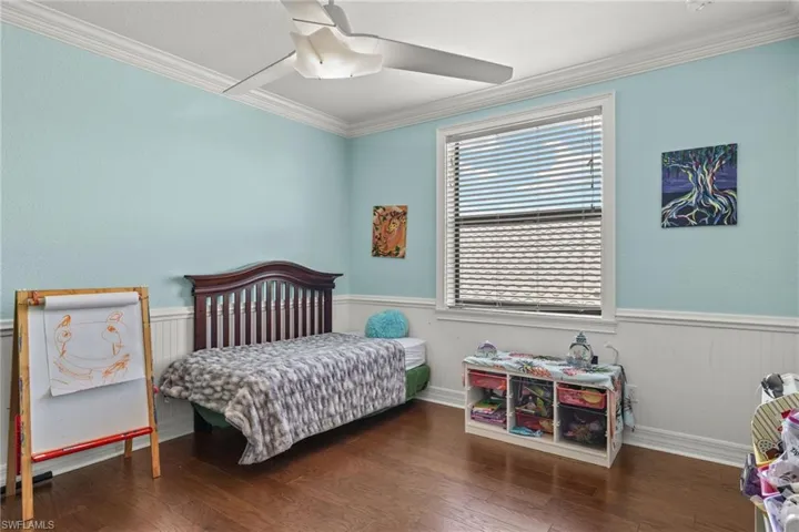 Bedroom #4 with dark wood-type flooring, ceiling fan, and crown molding