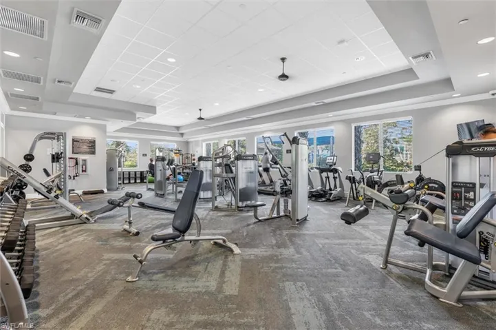 24 H Fitness Center with a paneled ceiling and a tray ceiling